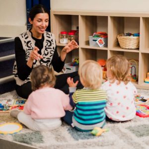 Nursery teacher playing with children during indoor activity